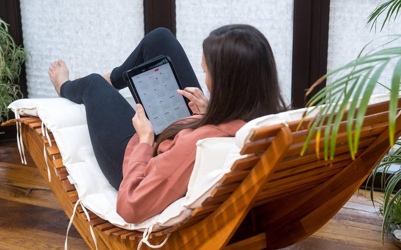 Eine Frau guckt auf einem Tablet auf einen Kalender