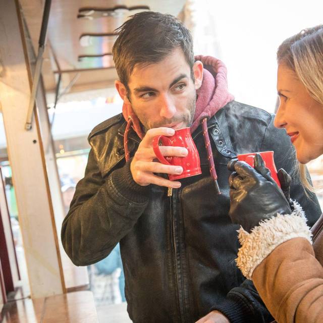Ein Mann und eine Frau trinken Heißgetränk auf Weihnachtsmarkt